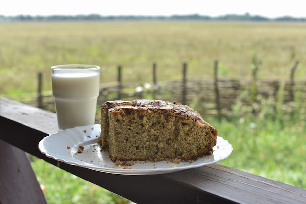 Bollo con semillas de amapola con un vaso de leche. Leche en un vaso y pastel de semillas de amapola en un campo