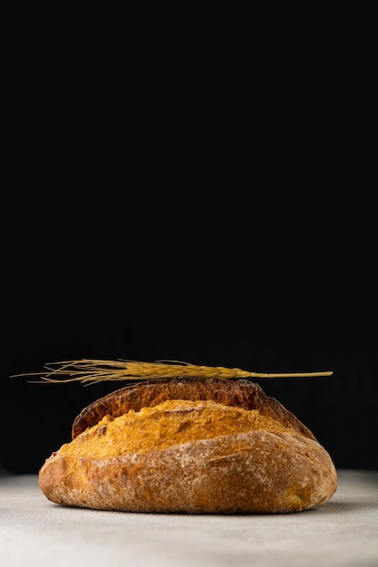 Bollo de trigo fresco sobre una mesa de luz sobre un fondo negro