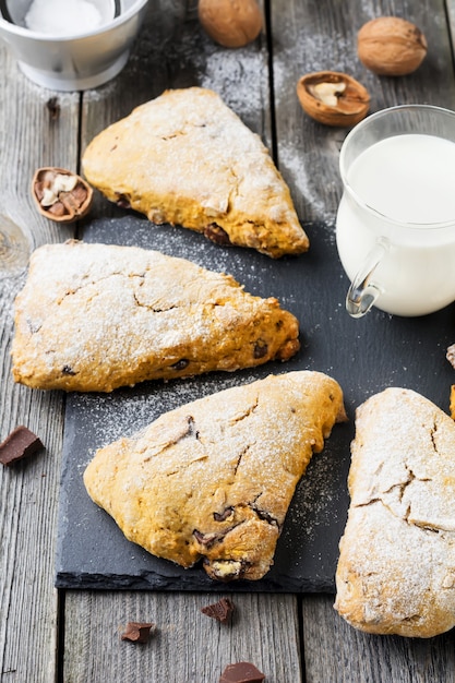 Bollos de calabaza con nueces y chocolate para el desayuno en una mesa de madera oscura.