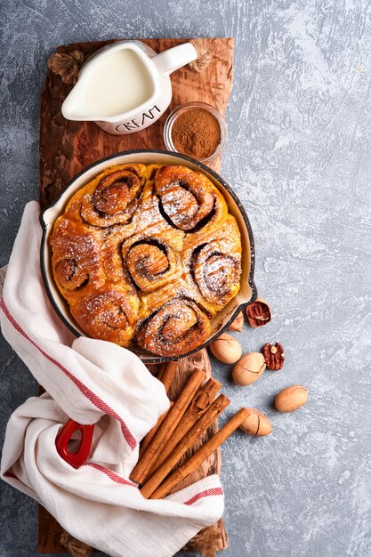 Bollos de canela y canela con calabaza, nuez, caramelo y crema de azúcar helada. Vista superior. Dulce repostería casera de Navidad para hornear. De cerca. Kanelbule - postre sueco.