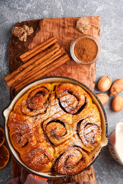 Bollos de canela y canela con calabaza, nuez, caramelo y crema de azúcar helada. Vista superior. Dulce repostería casera de Navidad para hornear. De cerca. Kanelbule - postre sueco.