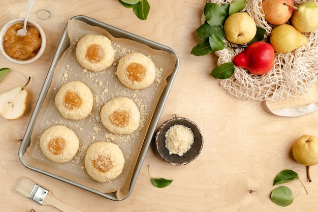 Bollos caseros crudos hechos de masa de levadura con mermelada y peras frescas Mini tartas Receta de cocina sobre un fondo de madera