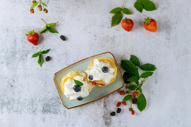 Bollos con crema batida y frutos del bosque.