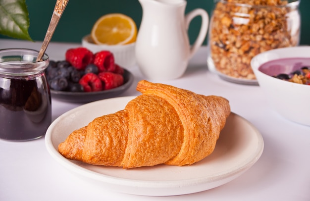 Bollos de cruasanes recién hechos, bayas, mermelada de grosella negra y tazón de batido. Concepto de desayuno.