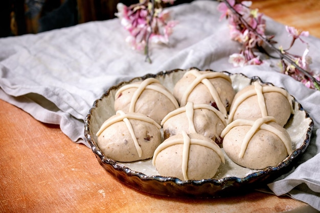 Bollos cruzados calientes tradicionales de Pascua caseros crudos sin hornear