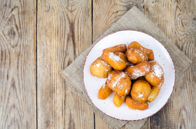 Bollos de donuts de cuajada dulce con azúcar en polvo en la mesa de madera.