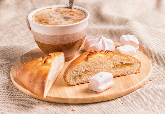 Bollos dulces, merengues y taza de café en una tabla de madera