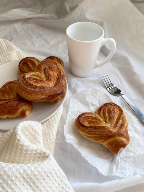 Bollos dulces en un plato blanco con una taza de té blanca