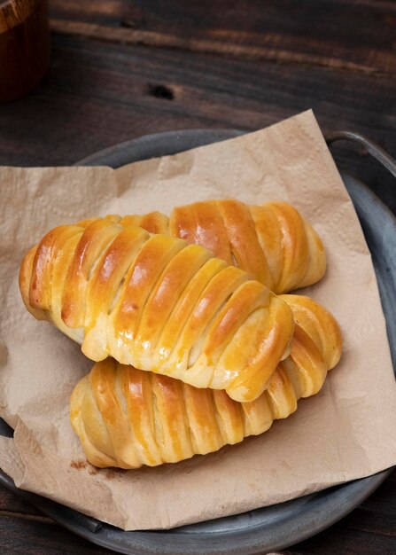 Foto bollos dulces rellenos de chocolate, queso, plátanos servidos en un plato vintage de hierro. fondo oscuro