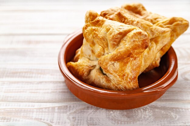 Bollos frescos con relleno de verduras Pan de trigo con relleno de verduras sobre un fondo de madera blanca