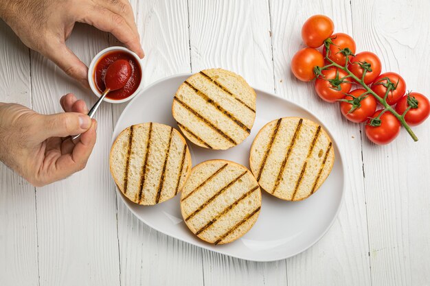 Bollos de hamburguesa en un plato blanco. Mesa de madera blanca