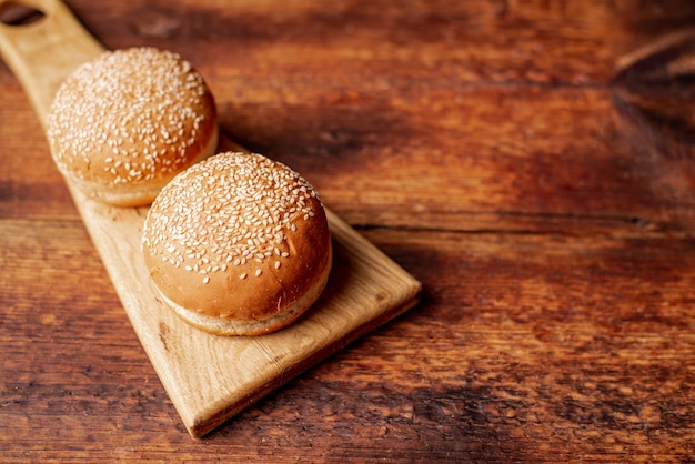 Bollos de hamburguesa Semillas de sésamo en la parte superior Fondo de madera Concepto de comida Lugar para el texto