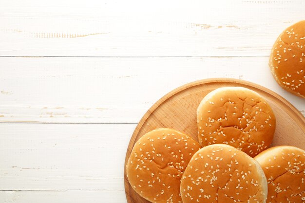 Bollos de hamburguesa en la tabla de cortar sobre un fondo de madera blanca. Vista superior.