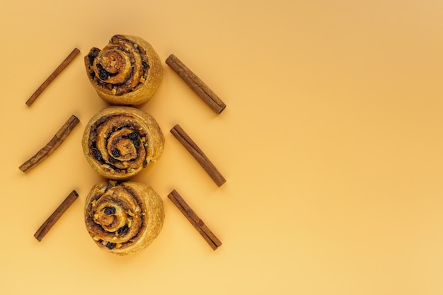 Bollos con nueces, pasas y canela en forma de árbol de Navidad sobre un fondo naranja