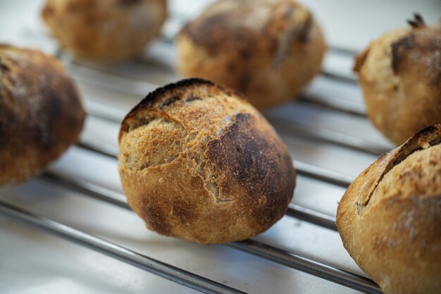 Bollos de pan de masa fermentada caseros recién horneados que se enfrían en un rastrillo