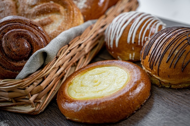 Bollos de pastelería fresca en la canasta en panadería de estilo rústico con trigo blanco sobre mesa de madera