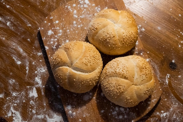 bollos pequeños con semillas de sésamo en una tabla espolvoreada con vista superior de harina. Panadería fresca. desayuno de comida