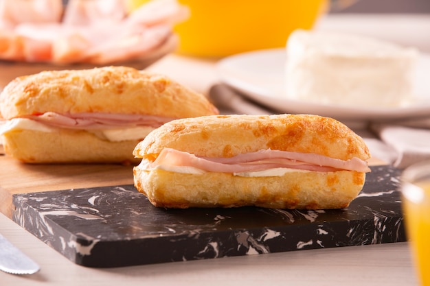 Bollos de queso brasileño con queso y jamón. Café de mesa por la mañana con pan de queso.