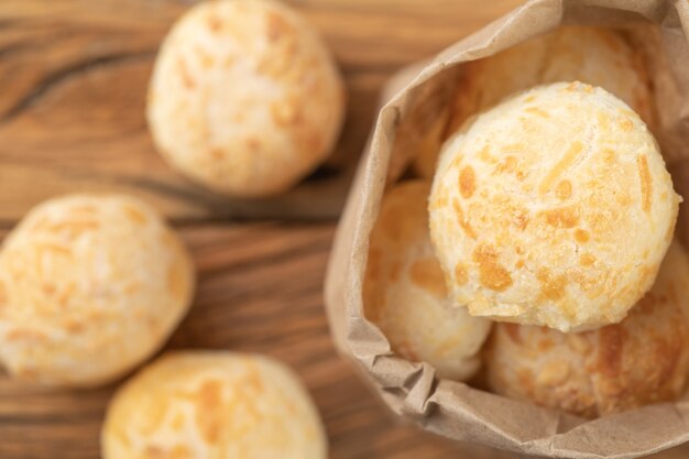 Bollos de queso típicos brasileños en una bolsa de papel sobre mesa de madera.