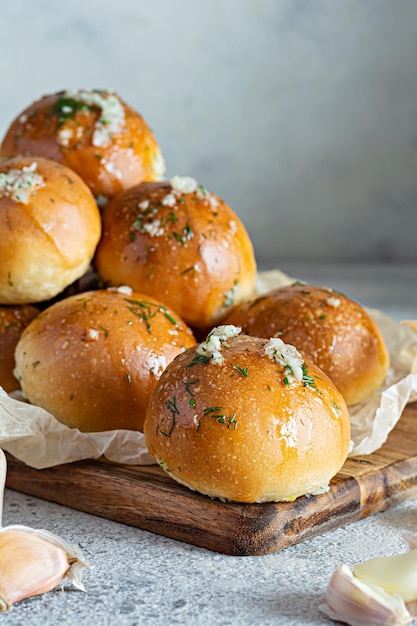 Bollos recién horneados (pampushki) con ajo y eneldo para el primer plato (sopa) sobre una tabla de madera.