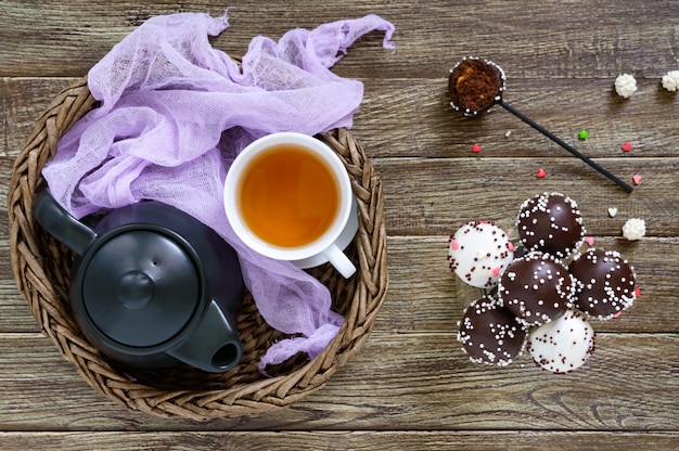 Bolo aparece. Rodada de doces no palito com cobertura de chocolate. Uma xícara de chá.