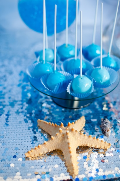 Bolo azul aparece no pano de prata. Tema da hora do mar na barra de chocolate da festa.