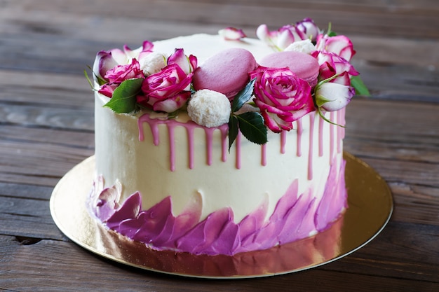 Bolo branco com uma decoração de rosa em uma mesa de madeira