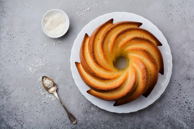 Bolo bundt com cobertura de açúcar e coco na superfície de concreto velho cinza escuro. foco seletivo.