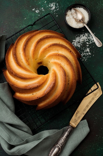 Bolo Bundt com cobertura de açúcar e coco na superfície de concreto velho verde escuro. Foco seletivo. Vista do topo