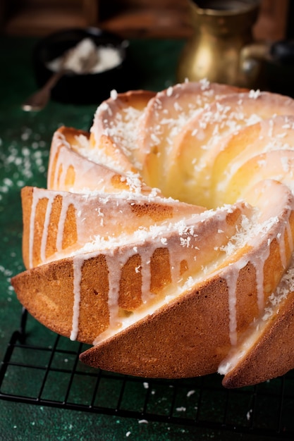 Bolo bundt com cobertura de açúcar e coco na superfície de concreto velho verde escuro. foco seletivo.