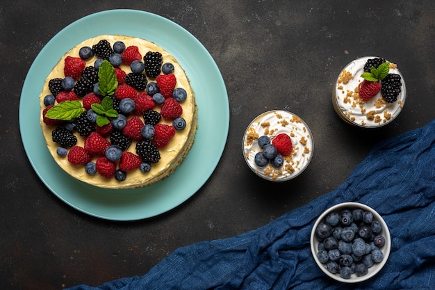 Bolo caseiro com frutas frescas e sobremesas doces na superfície escura.