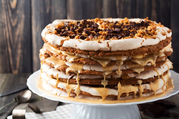 Bolo caseiro em camadas e merengue, nozes, chocolate amargo na madeira velha