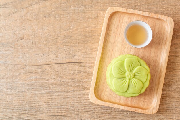 Bolo chinês de lua com sabor de chá verde com chá no prato de madeira