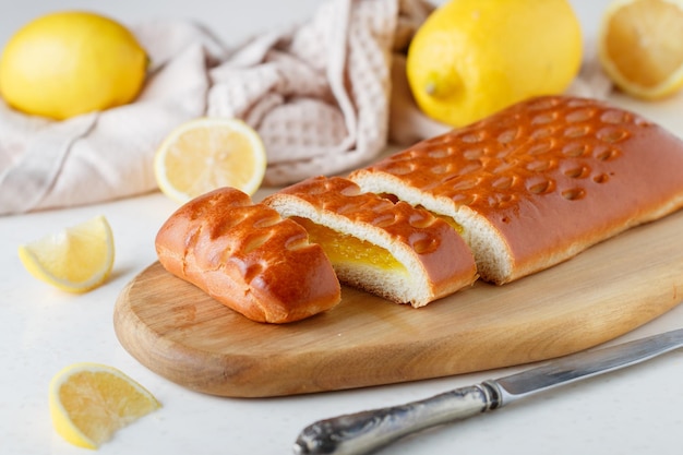 Foto bolo cítrico caseiro com geléia de limão em uma tábua de madeira sobre uma mesa branca estilo rústico foco seletivo