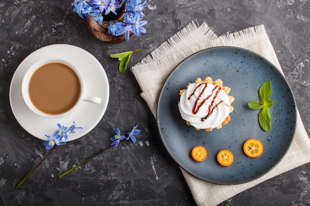 Bolo com chantilly creme de ovo em uma placa de cerâmica azul com kumquat e folhas de hortelã