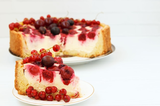 Bolo com frutas está localizado em um prato em um pedaço de bolo de fundo branco em primeiro plano