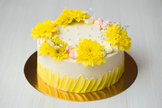 Foto bolo com manchas amarelas, crisântemos amarelos e merengue