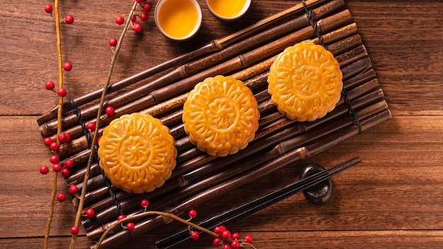 Bolo da lua, mesa de bolo da lua, pastelaria tradicional chinesa com xícaras de chá em fundo de madeira, conceito do Festival do Meio Outono, vista superior plana