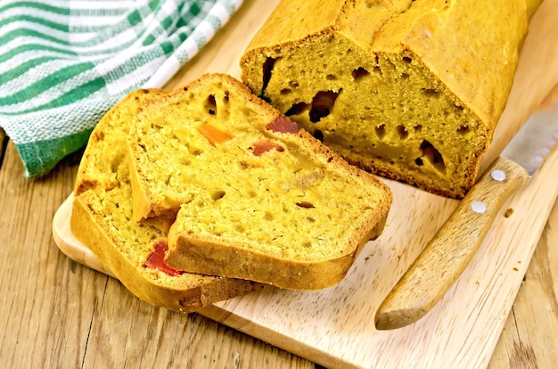 Bolo de abóbora com frutas cristalizadas no quadro, faca, guardanapo no fundo de tábuas de madeira