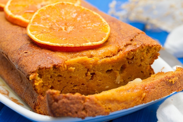 Foto bolo de abóbora com laranja no prato branco na superfície de madeira