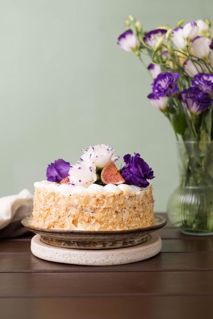 Bolo de amêndoa com figos e flores em uma mesa rústica com um buquê de flores em um vaso