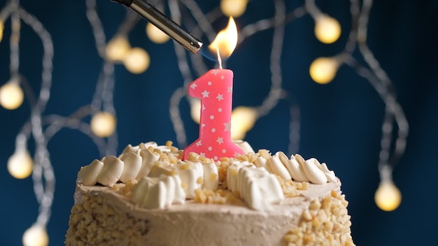 Bolo de aniversário com 1 vela rosa número backgraund azul incendiado por isqueiro. Vista de perto