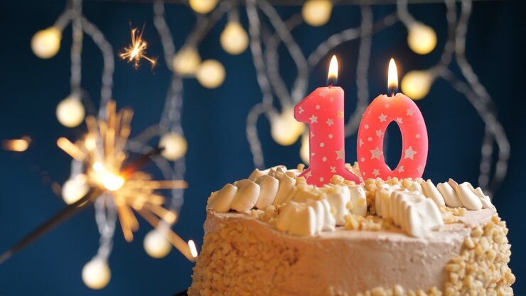 Foto bolo de aniversário com 10 velas rosa número e diamante aceso em fundo azul. fechar-se
