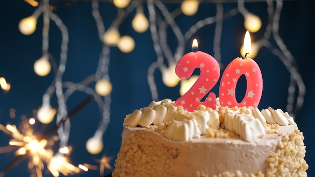 Bolo de aniversário com 20 velas rosa número e diamante aceso em fundo azul. fechar-se