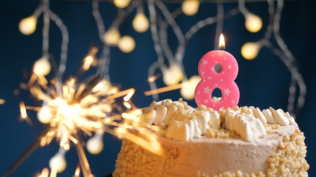 Bolo de aniversário com 8 velas rosa número e diamante aceso em fundo azul. Fechar-se