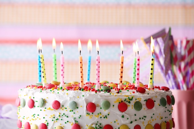 Bolo de aniversário com vela em fundo listrado colorido