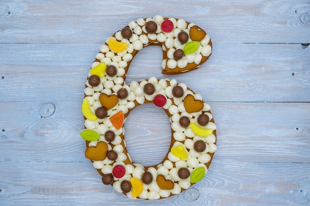 bolo de aniversário em forma de seis figuras sobre fundo de madeira