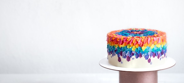 Bolo de aniversário multicolorido decorado com creme brilhante. Conceito de bolos personalizados.