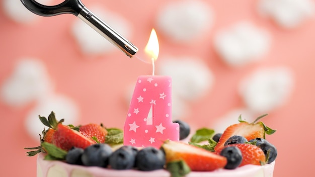 Bolo de aniversário número 4 vela rosa no lindo bolo com bagas e isqueiro com fogo contra o fundo de nuvens brancas e céu rosa Vista aproximada