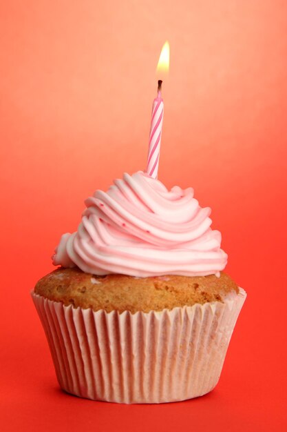 Foto bolo de aniversário saboroso com vela em fundo vermelho